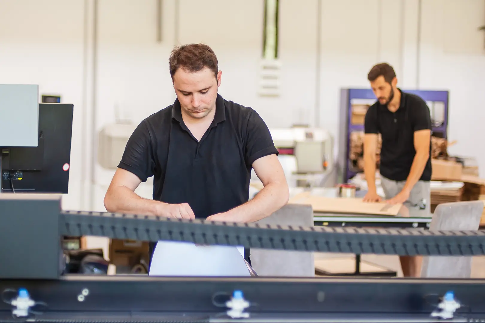 Two men working hard in a digital printing press shop to keep the workflow running efficiently